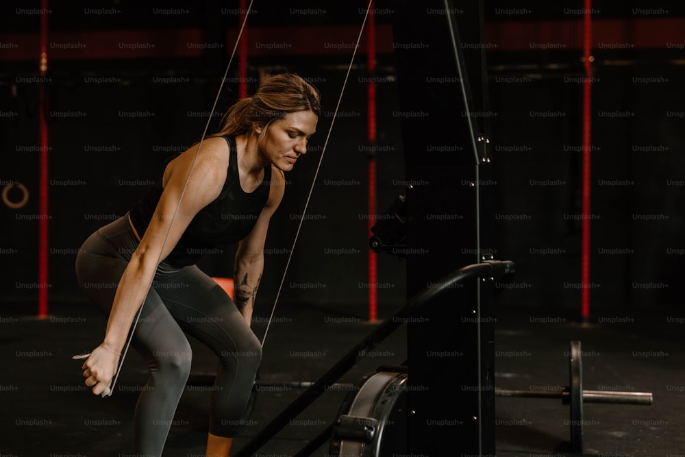 Eine Frau, die in einem Crossfit-Fitnessstudio auf einer Bar hockt