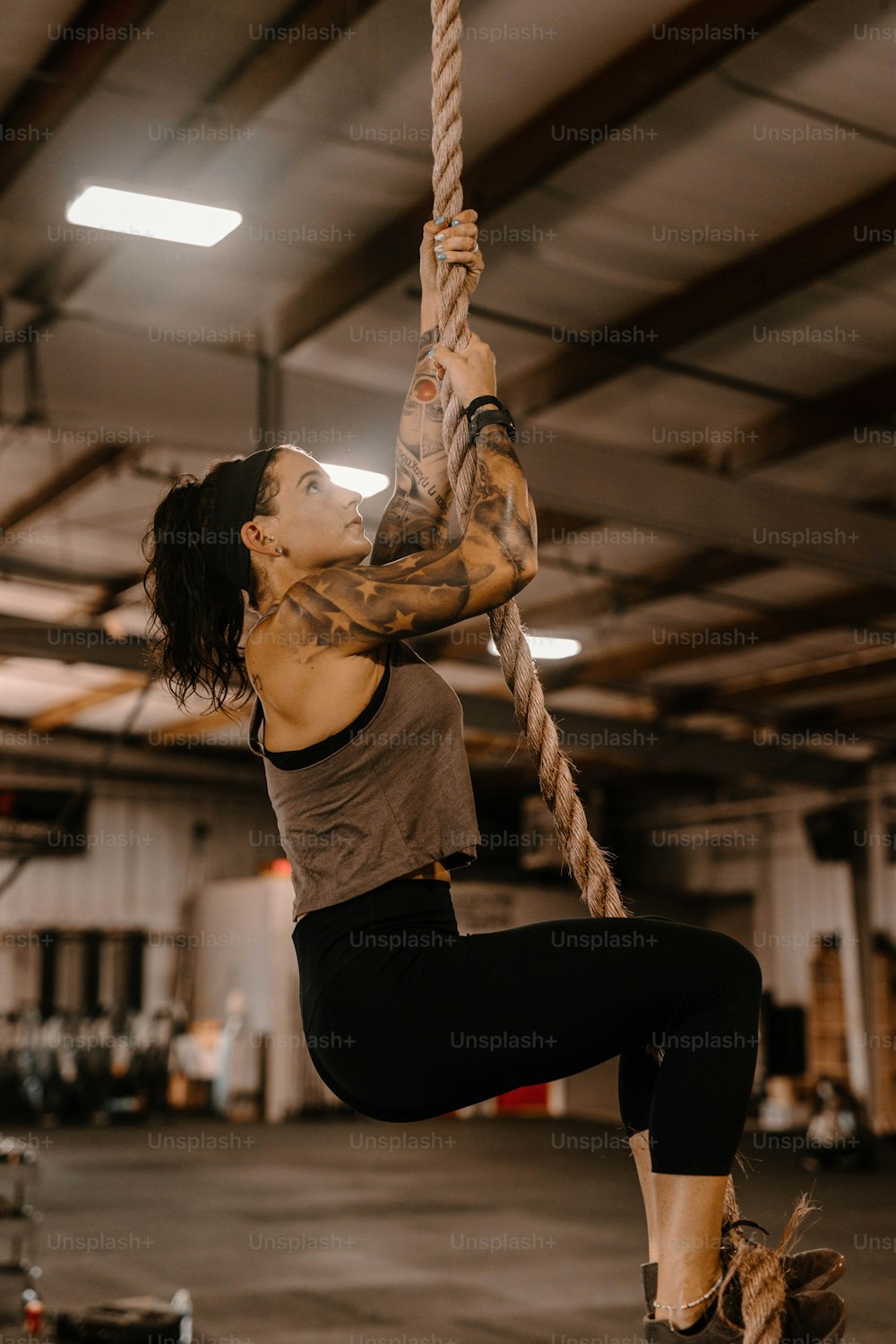 a woman hanging on a rope in a gym