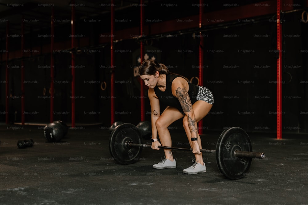 a woman squatting on a barbell in a gym