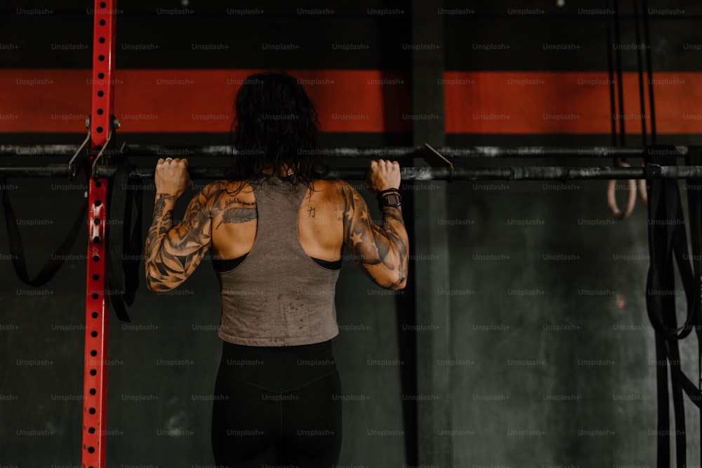 a woman with a tattoo on her back holding a bar