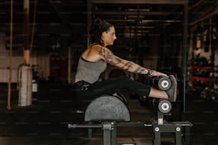 a woman sitting on a bench with a barbell