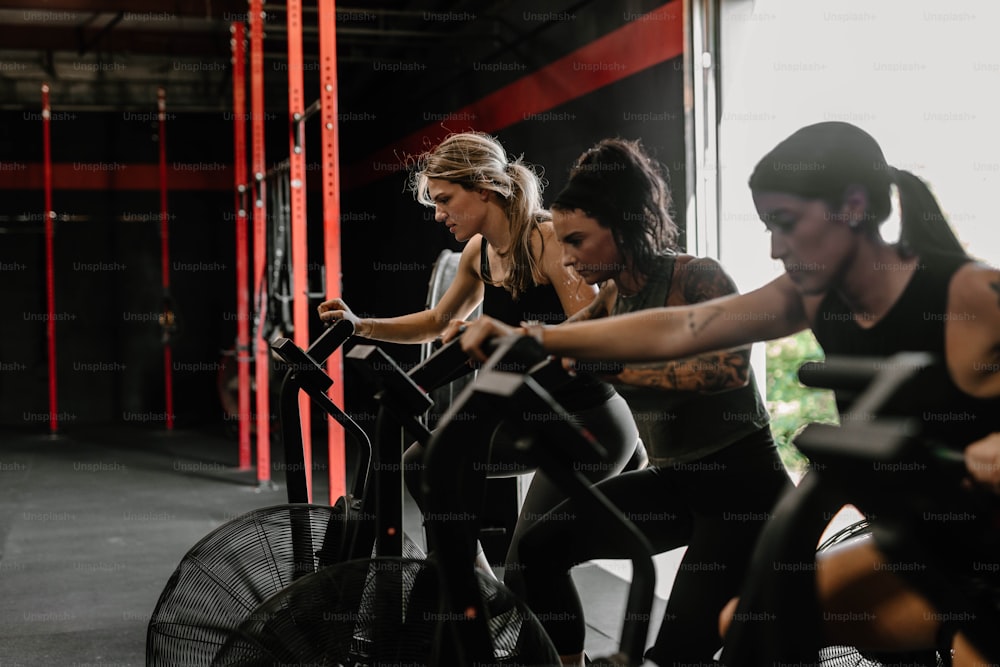 Eine Gruppe von Frauen, die in einem Fitnessstudio stationäre Fahrräder fahren