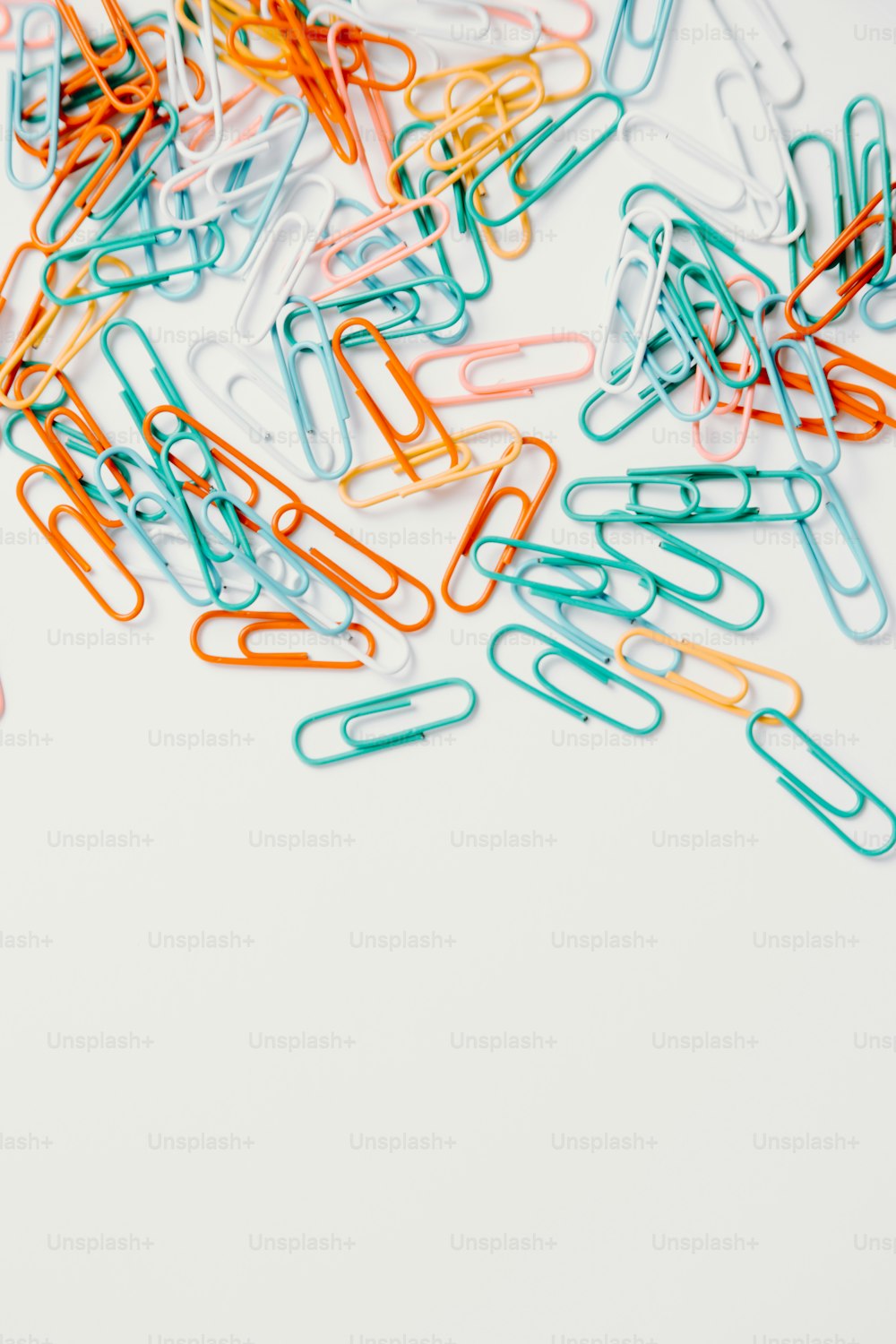 a pile of colored paper clips on a white surface