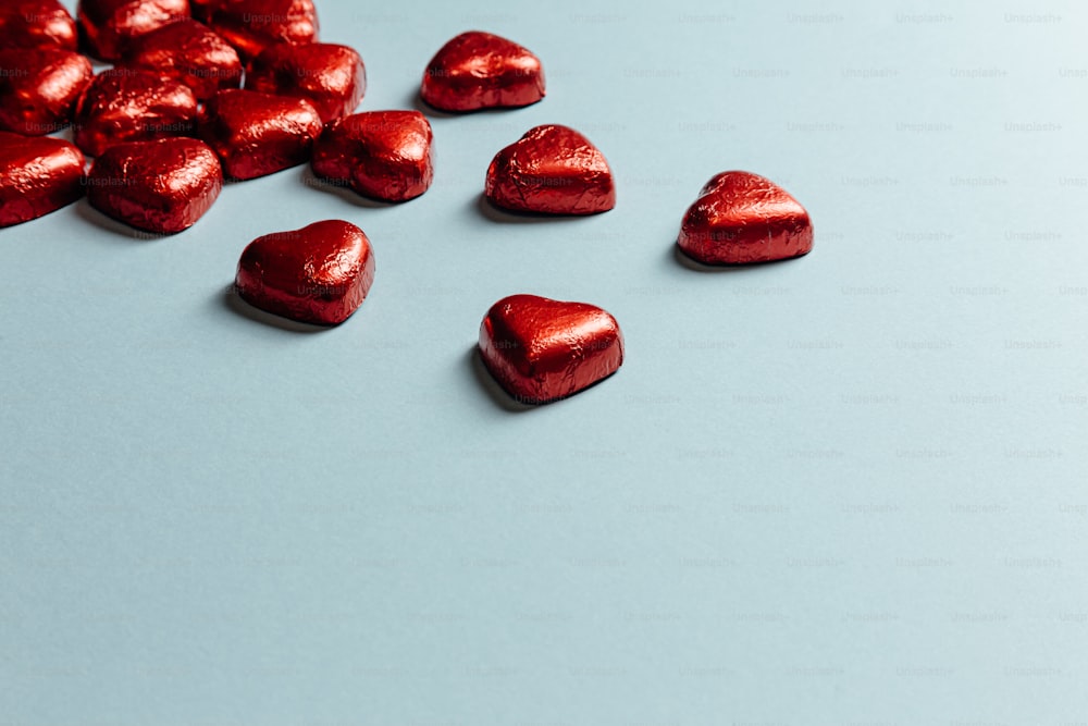 a pile of red heart shaped chocolates on a blue surface