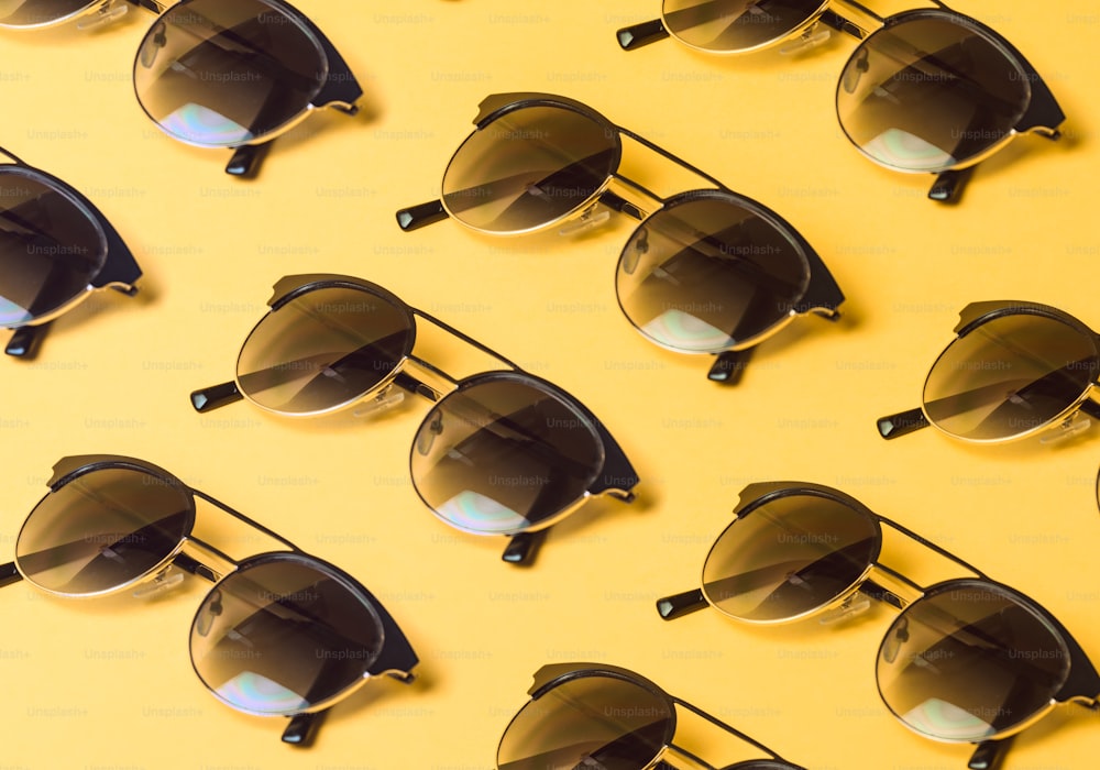 Un gruppo di occhiali da sole seduti sopra una superficie gialla