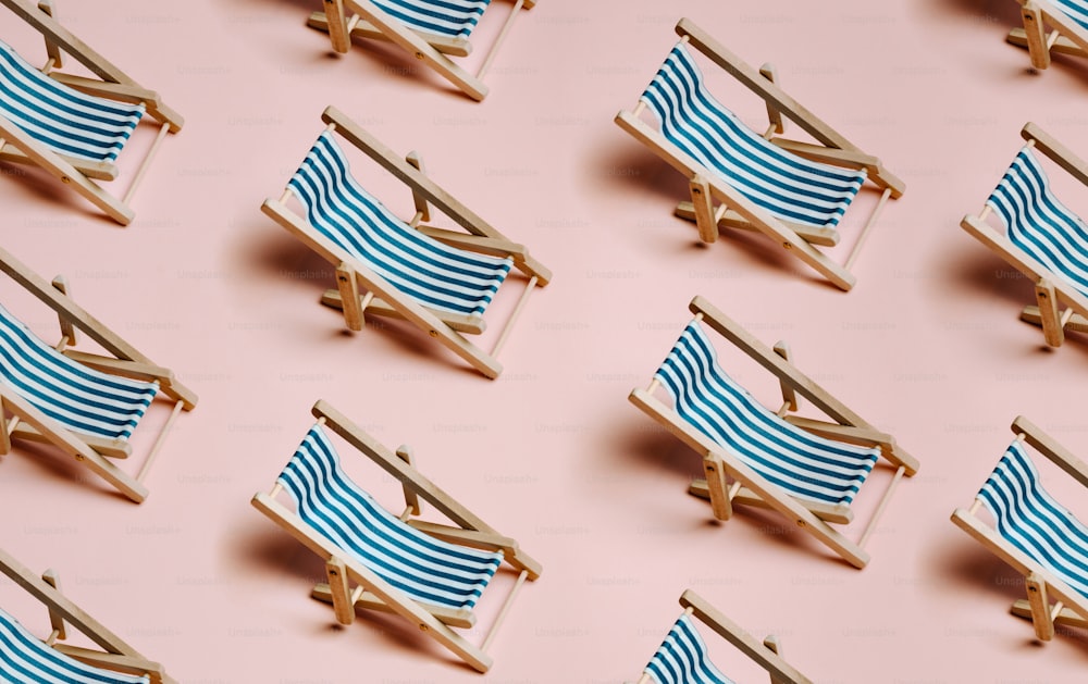 a row of blue and white beach chairs on a pink background
