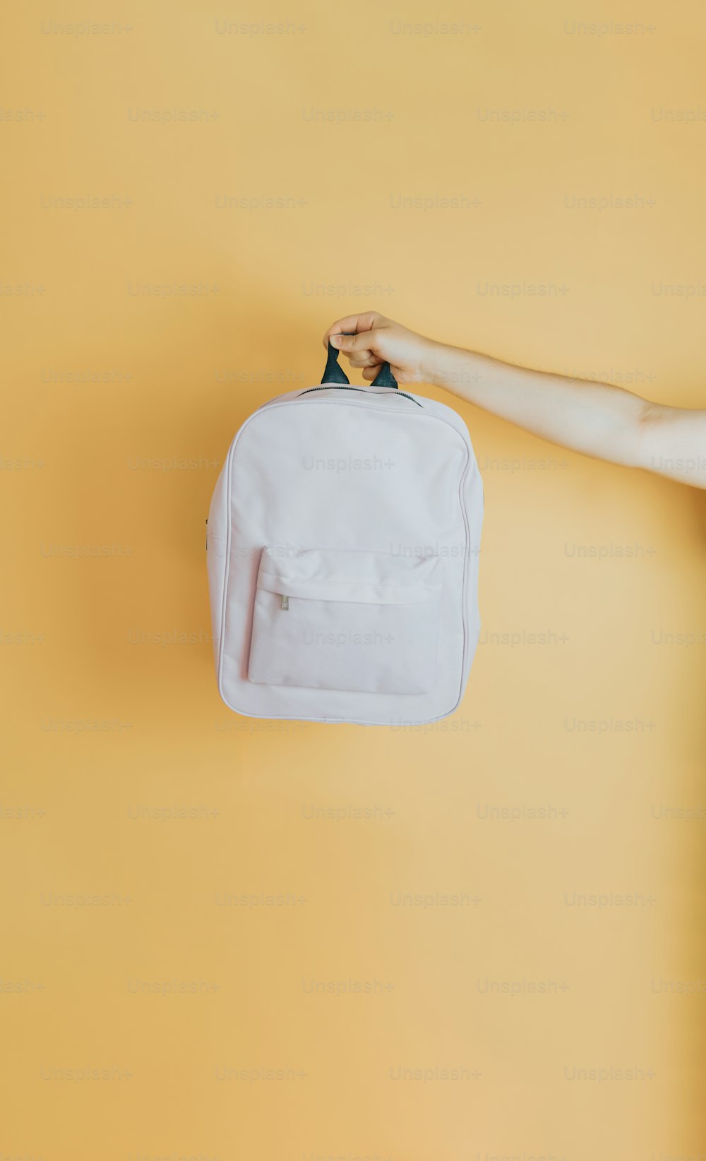 a white backpack hanging on a yellow wall