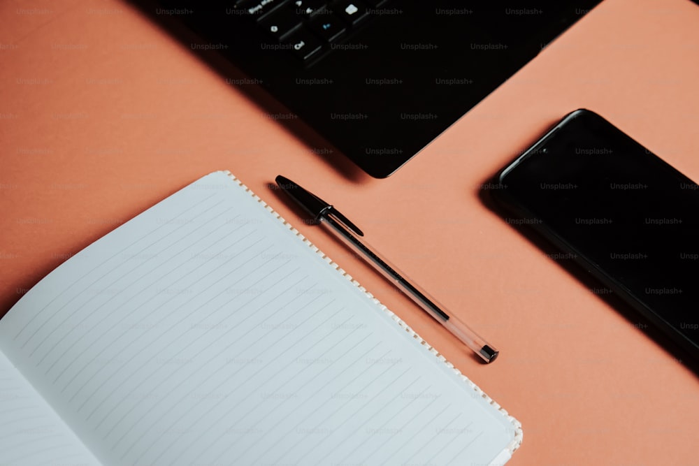 um caderno, caneta e laptop em uma mesa