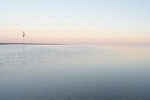 a body of water with a light pole in the distance