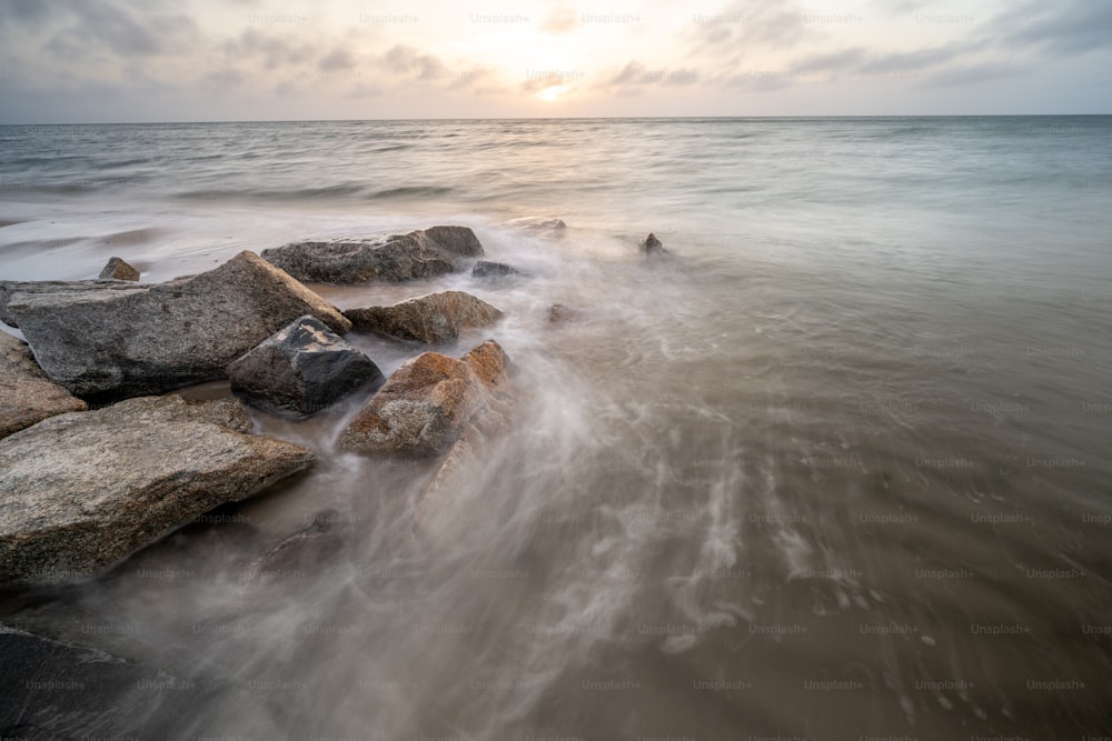 Una foto a lunga esposizione dell'oceano con rocce in primo piano