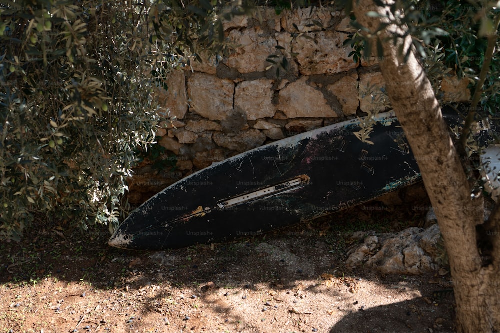 a black surfboard leaning against a stone wall