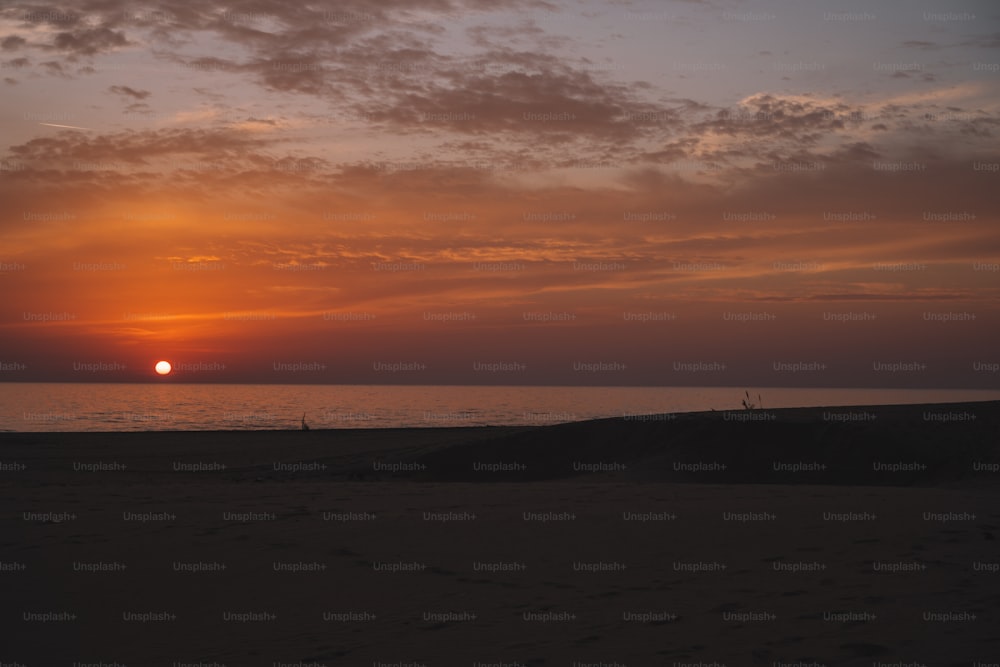 the sun is setting over the ocean on a cloudy day