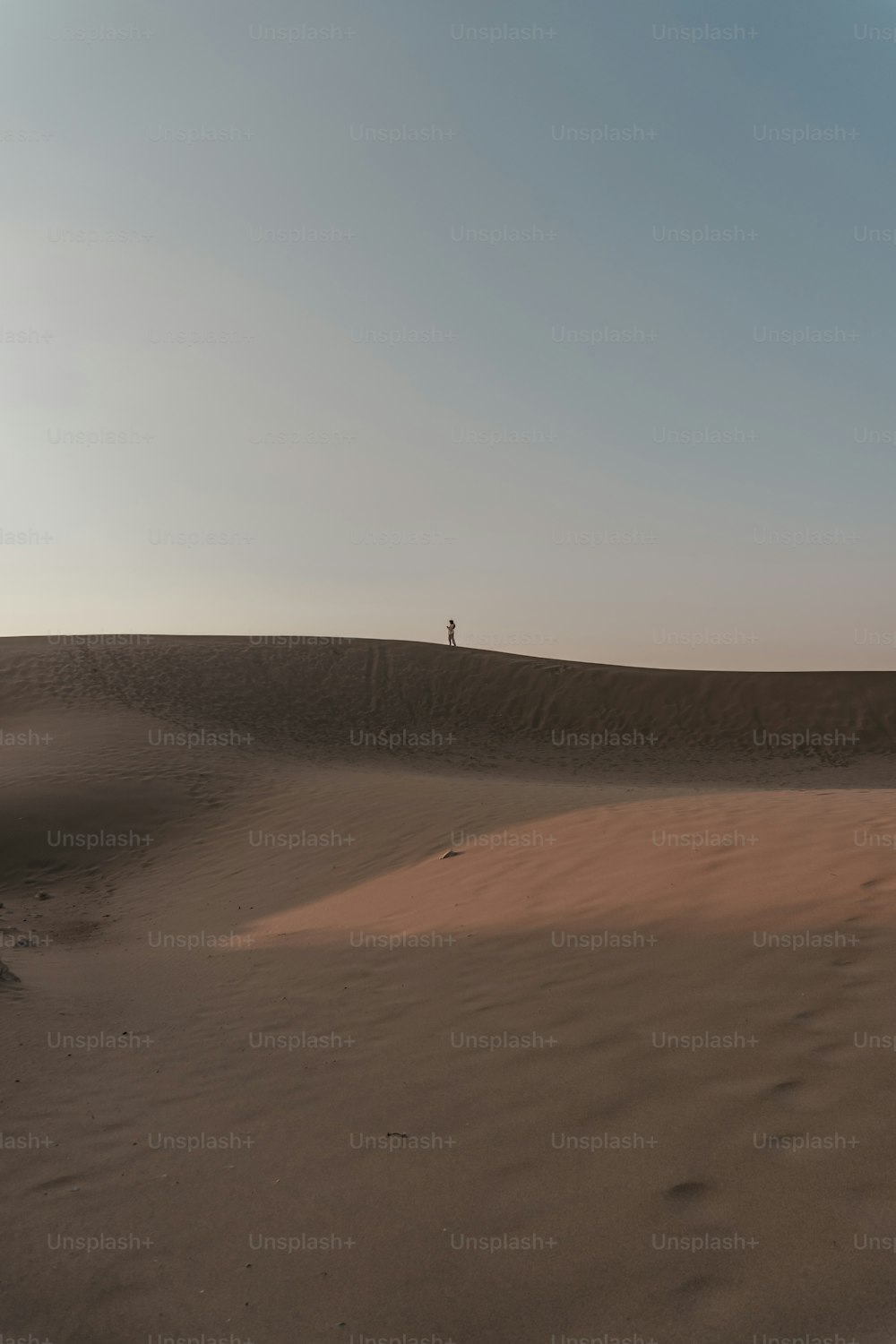 Una persona in piedi sulla cima di una duna di sabbia
