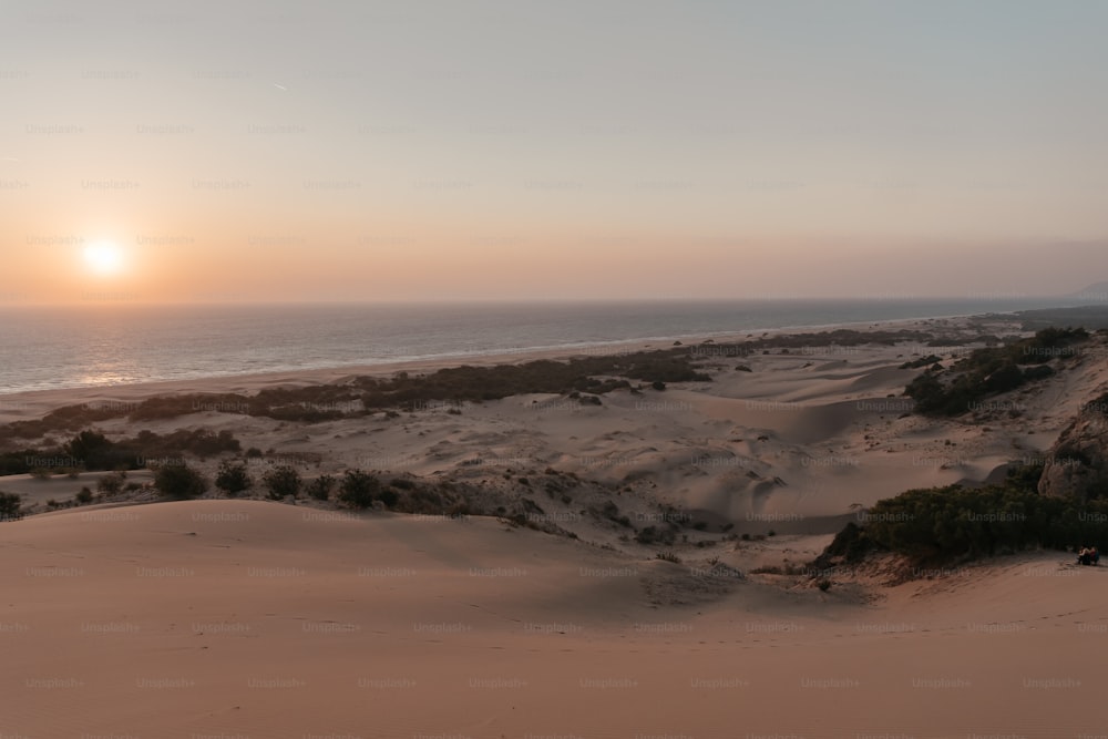 Die Sonne geht über einem Sandstrand unter