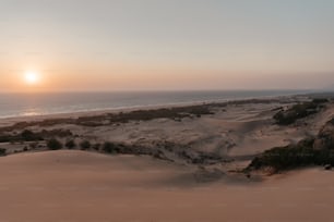 the sun is setting over a sandy beach