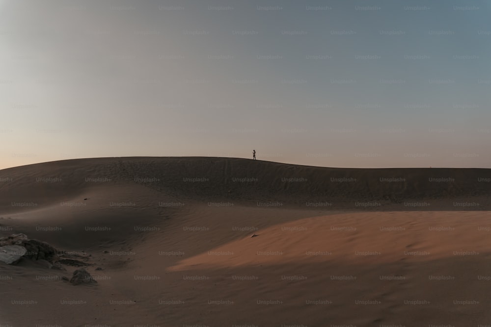 Una persona in piedi sulla cima di una duna di sabbia