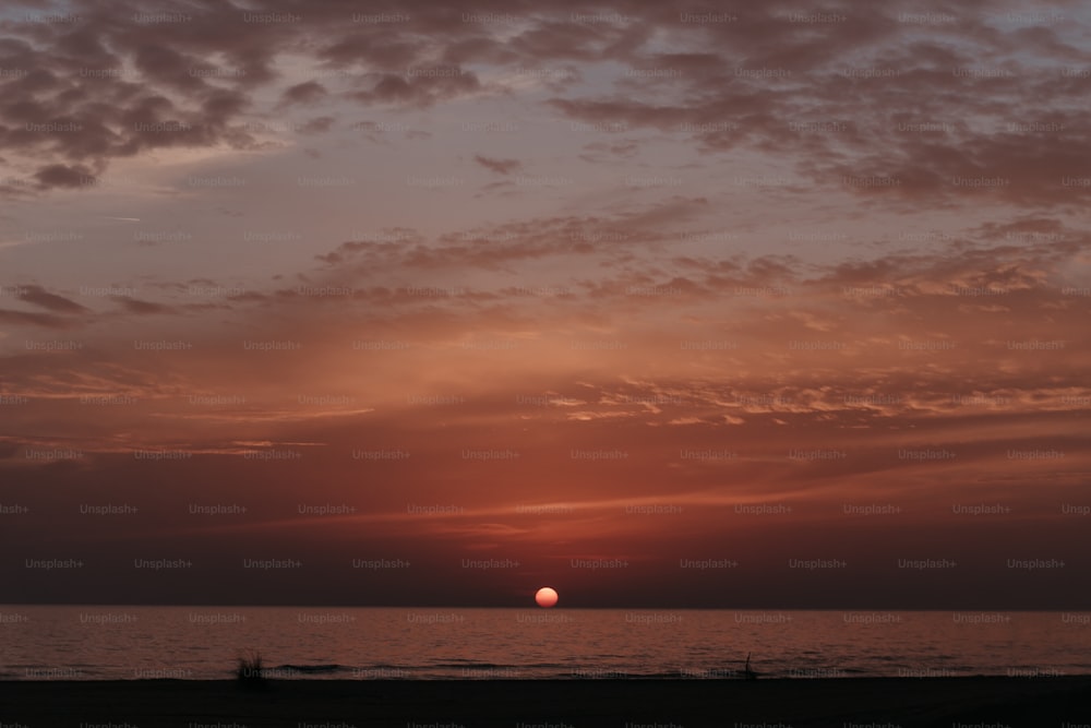 the sun is setting over the ocean on a cloudy day