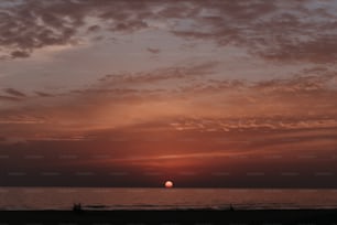 the sun is setting over the ocean on a cloudy day