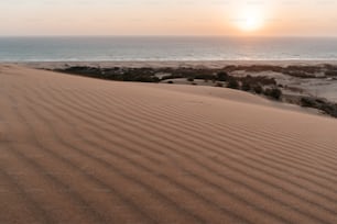 Die Sonne geht über dem Meer und den Sanddünen unter