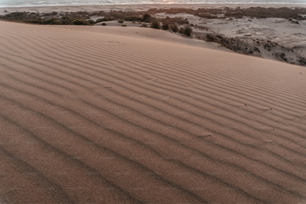 the sun is setting over a sandy beach