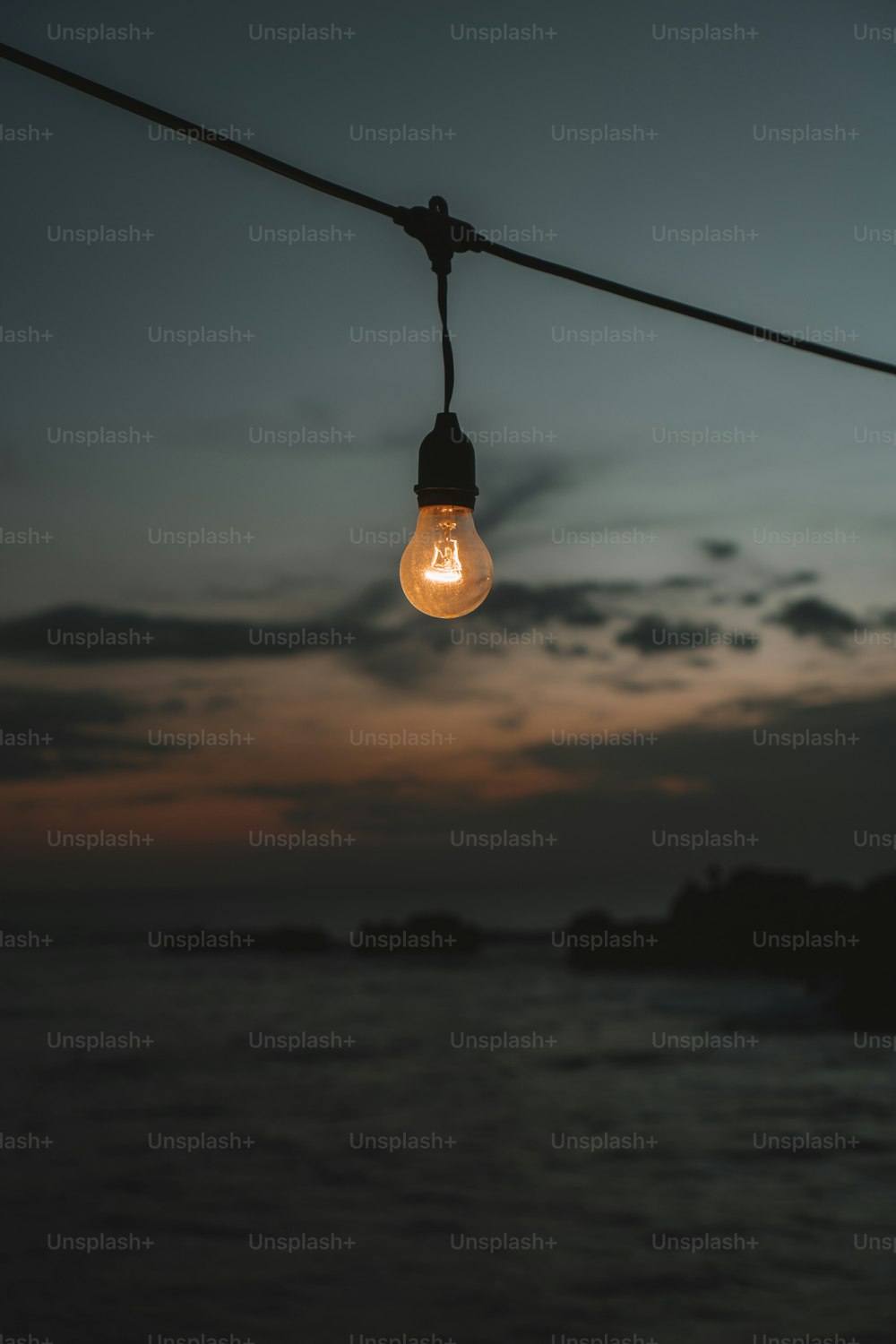 a light bulb hanging from a rope over a body of water