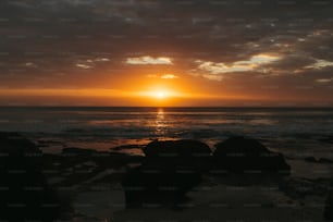 the sun is setting over the ocean on a cloudy day