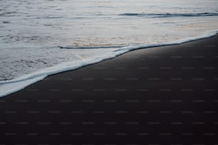 uma praia negra com ondas chegando à costa