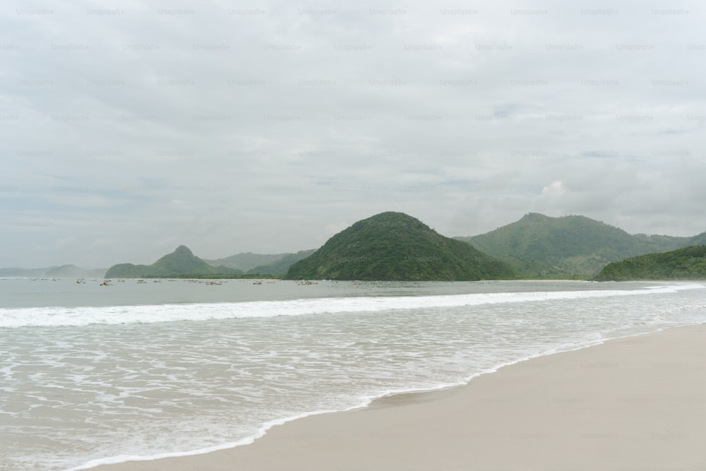 a sandy beach with mountains in the background