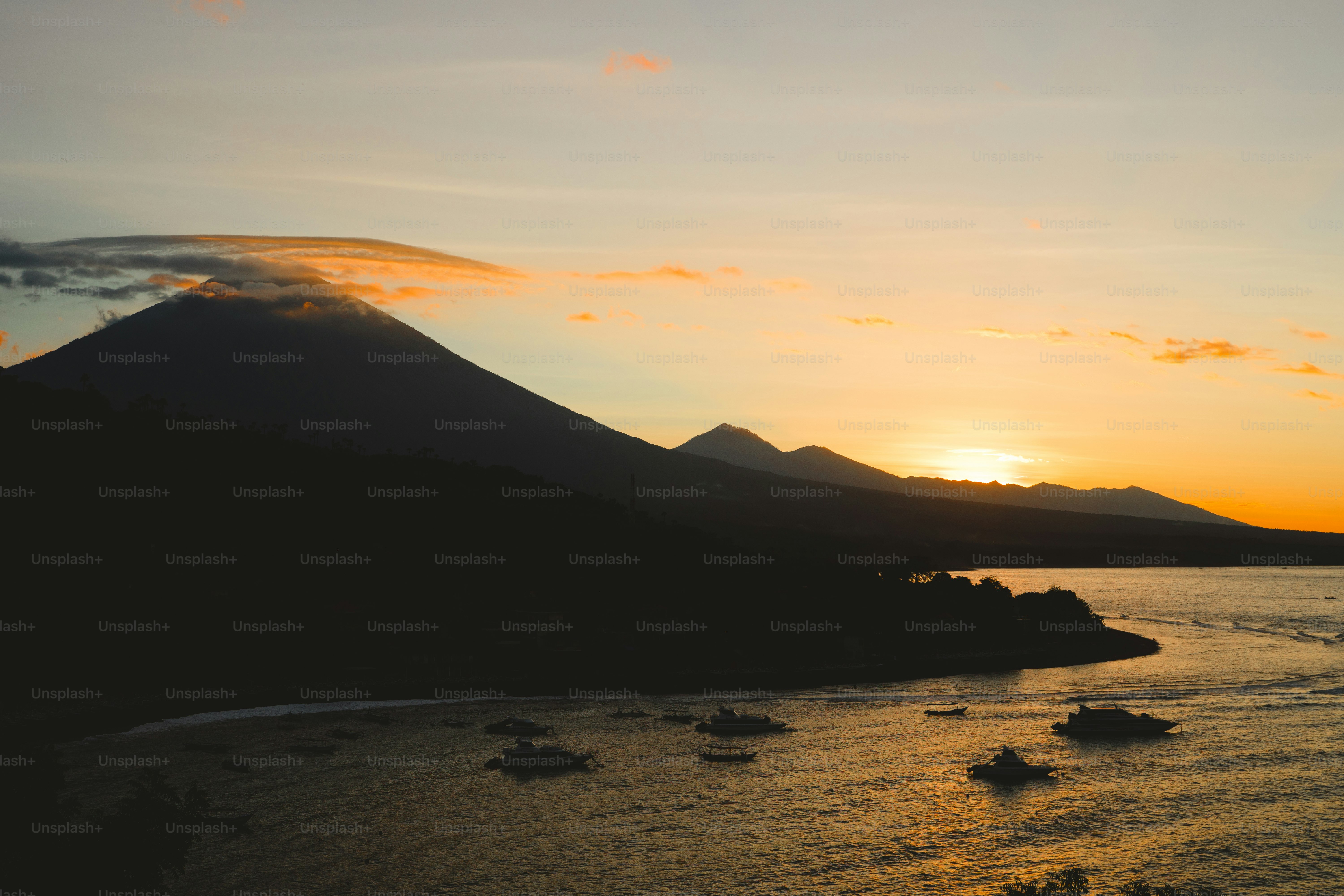 Un tramonto su uno specchio d'acqua con una montagna sullo sfondo