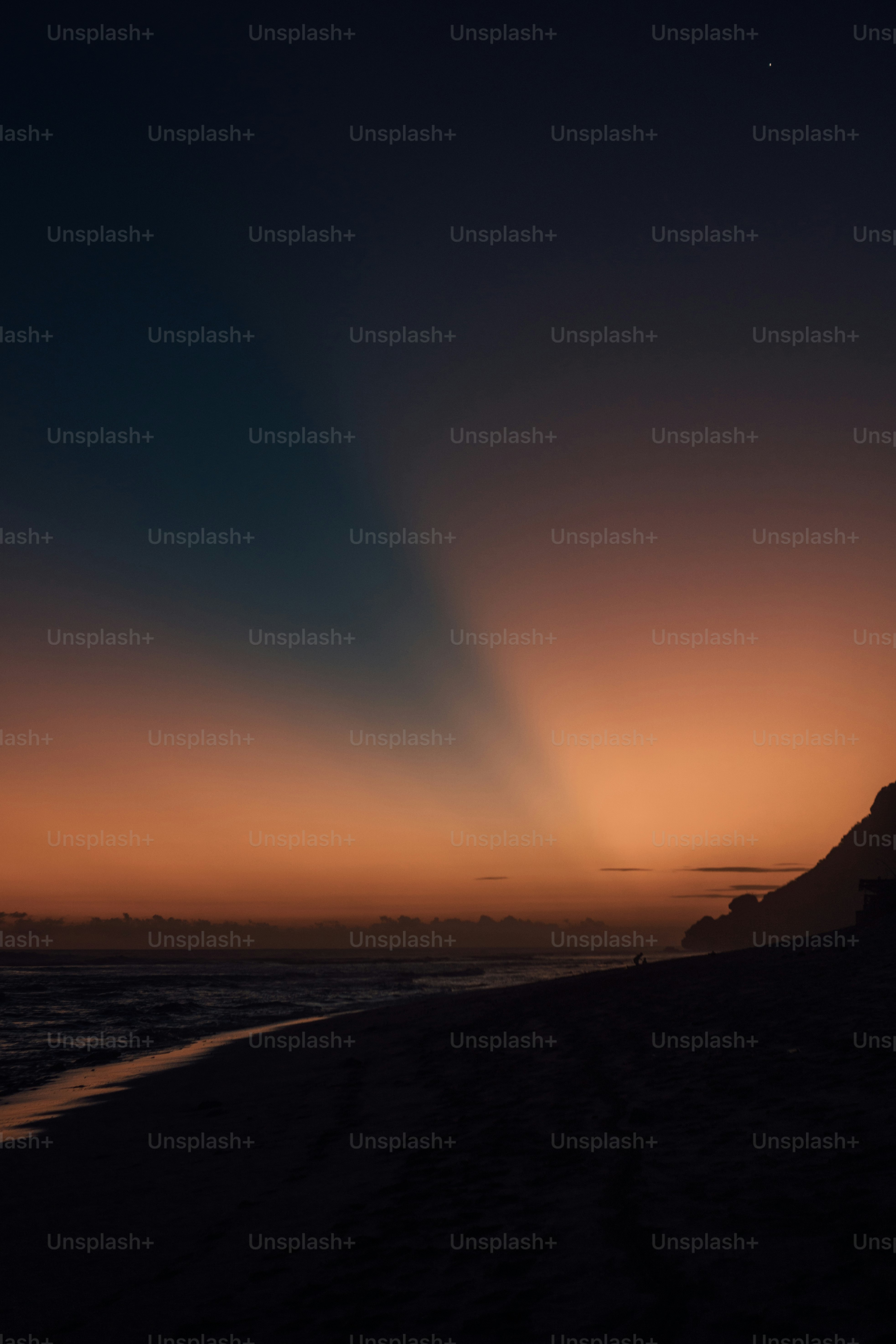 Il sole sta tramontando sull'oceano con una spiaggia in primo piano