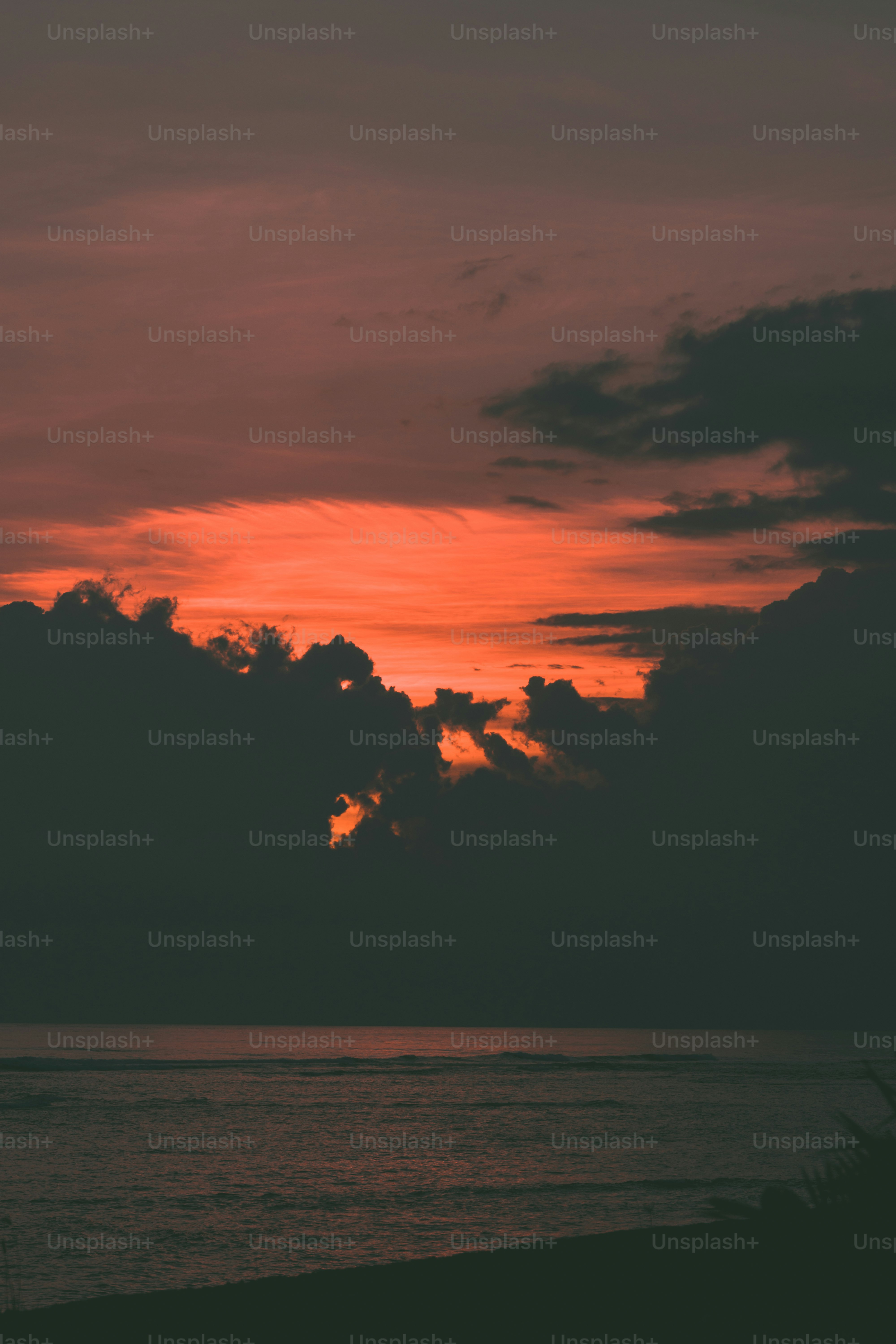 the sun is setting over the ocean with clouds