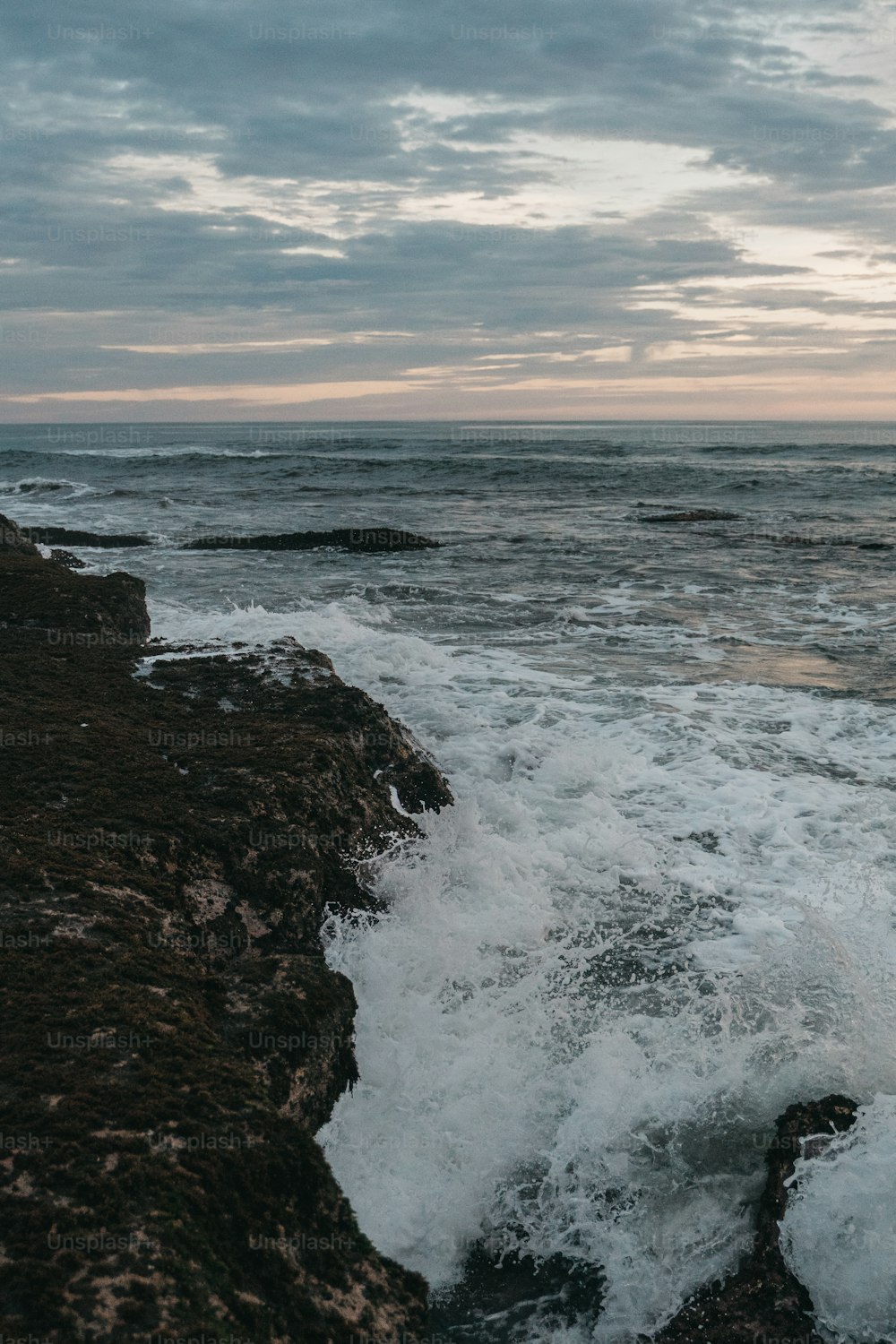 a person standing on top of a rocky beach next to the ocean