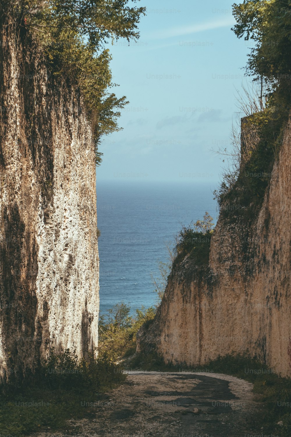 a dirt road next to a cliff near the ocean