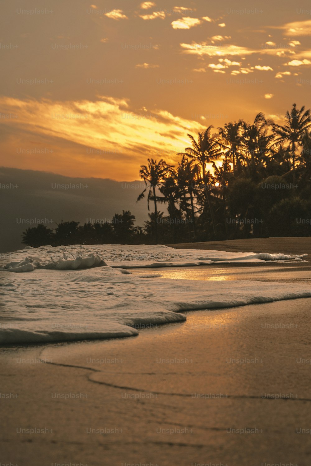 the sun is setting over the ocean with waves coming in