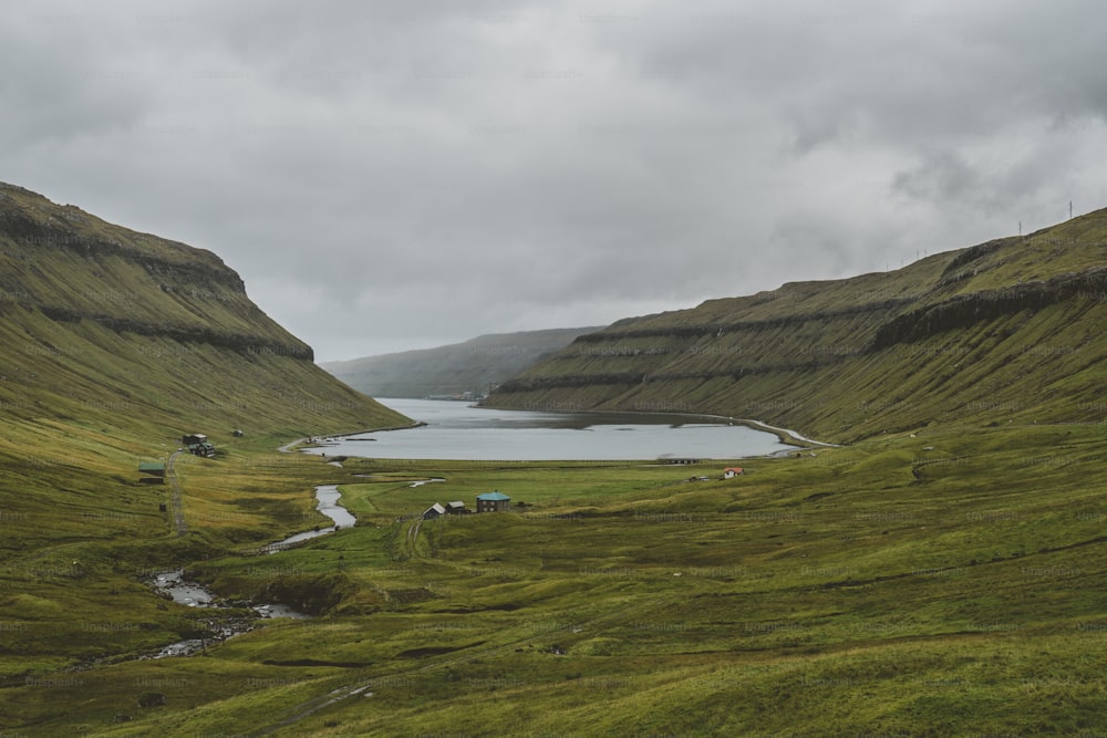 a grassy valley with a lake in the middle of it