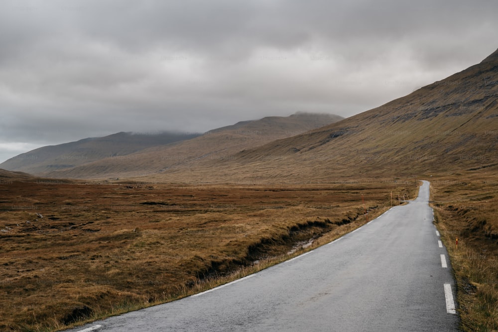 an empty road in the middle of a mountain range