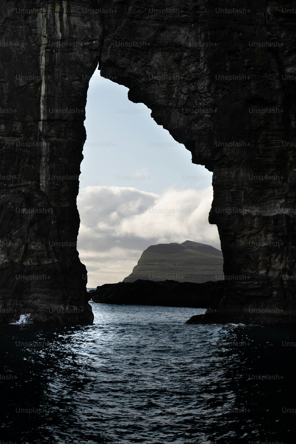 a view of the ocean through an arch in a rock formation