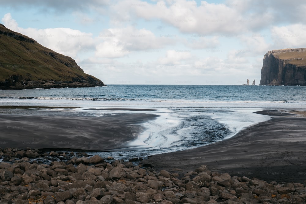 um grande corpo de água sentado ao lado de uma praia rochosa