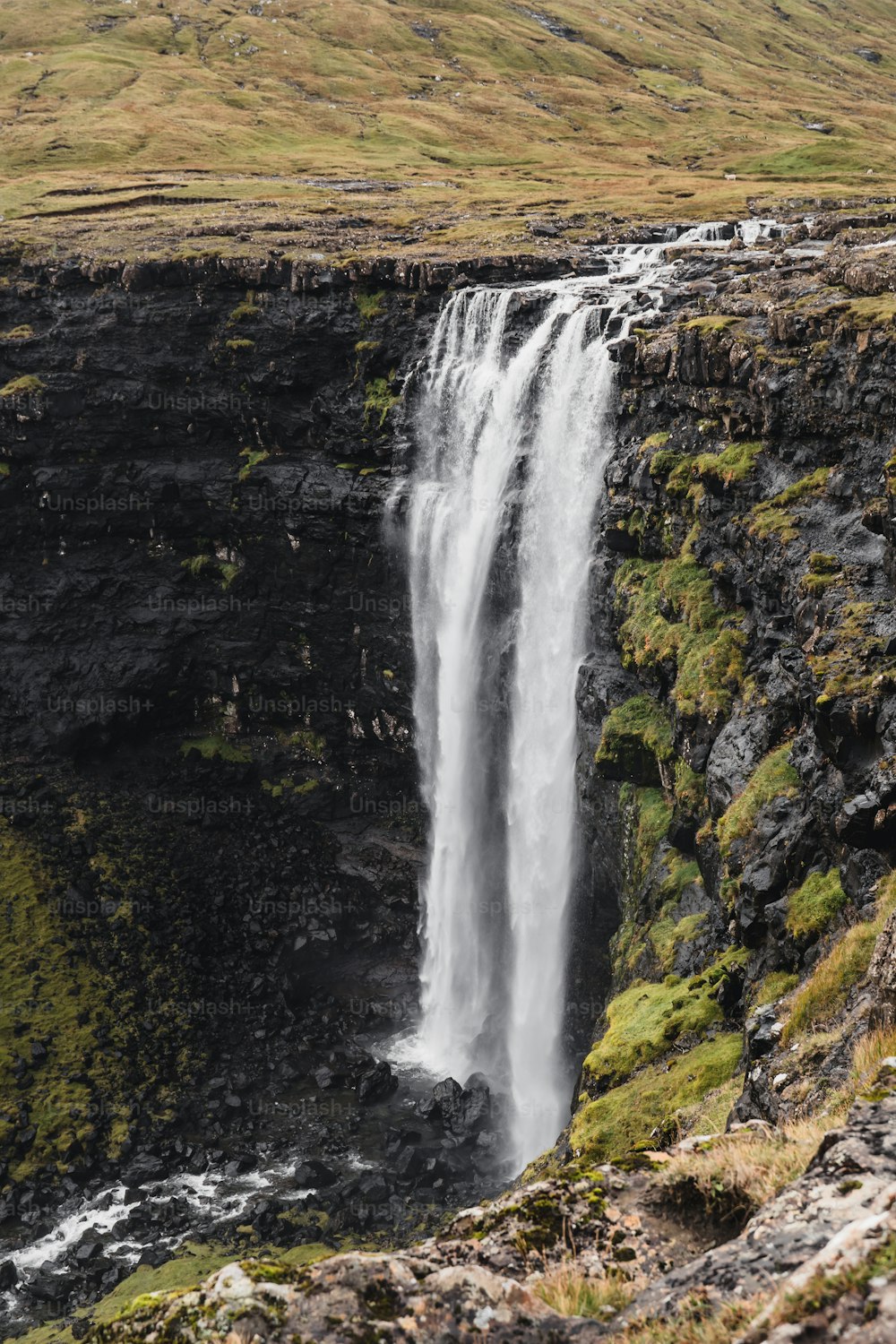 a waterfall with a man standing at the top of it