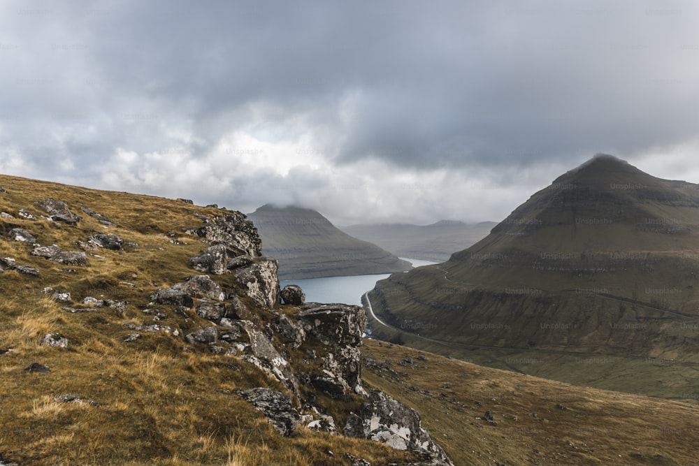 a grassy hill with a body of water in the distance