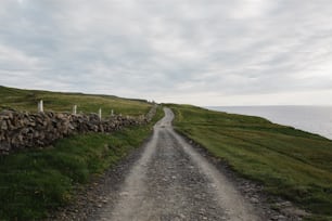 uma estrada de cascalho com um muro de pedra ao lado do oceano