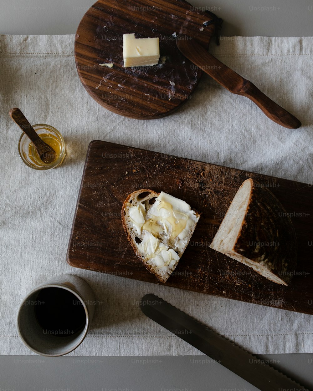 a wooden cutting board topped with cheese next to a cup of coffee