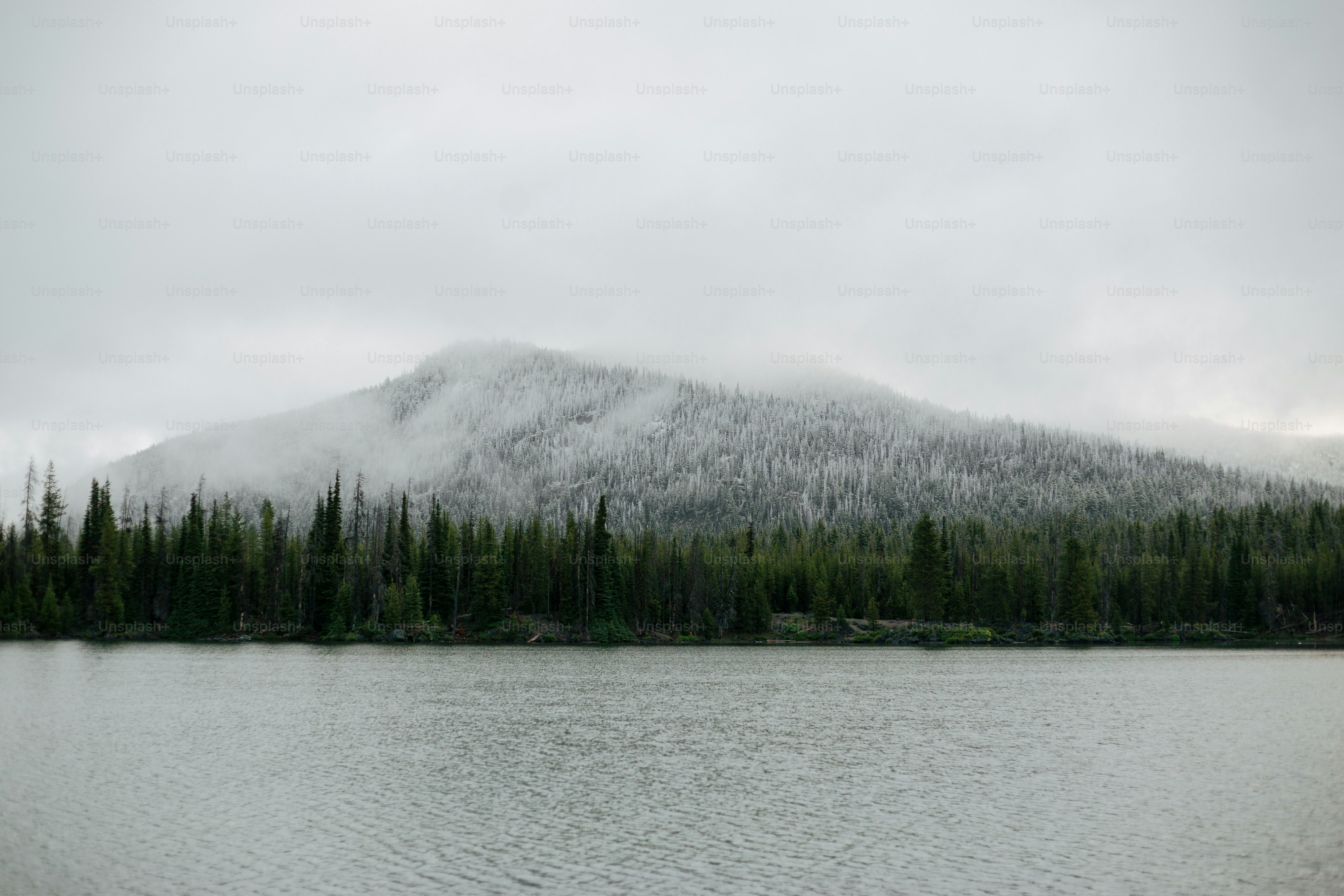 a mountain covered in snow next to a lake