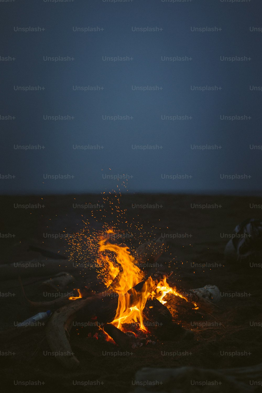 a campfire with bright orange flames in the middle of the night