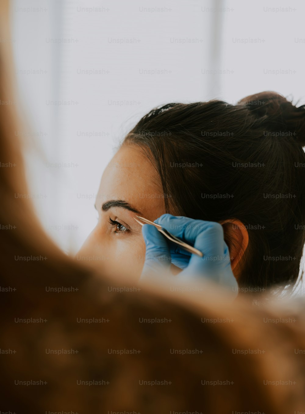 ヘアスタイリストに眉毛を整えられる女性