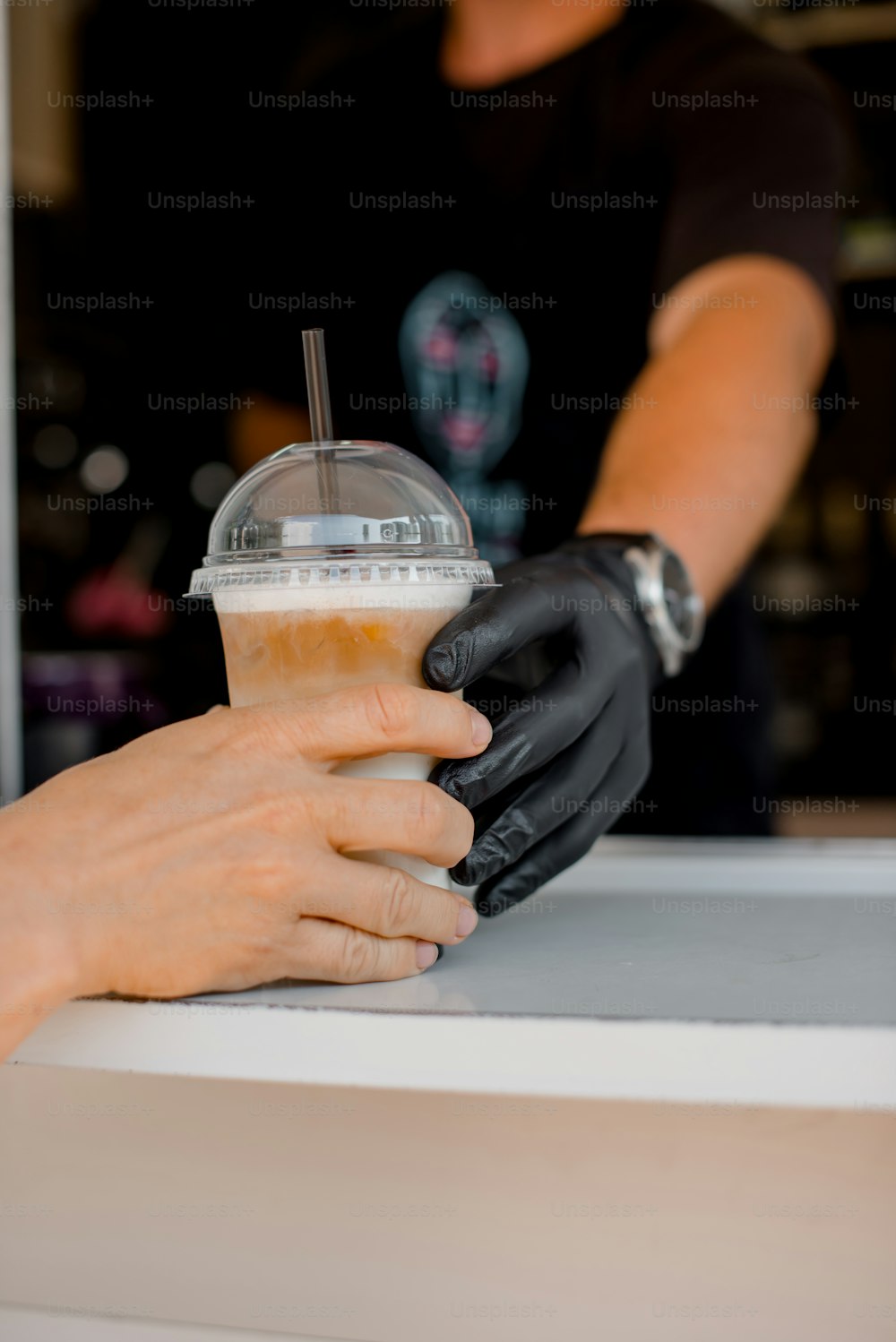 a person in black gloves is holding a drink