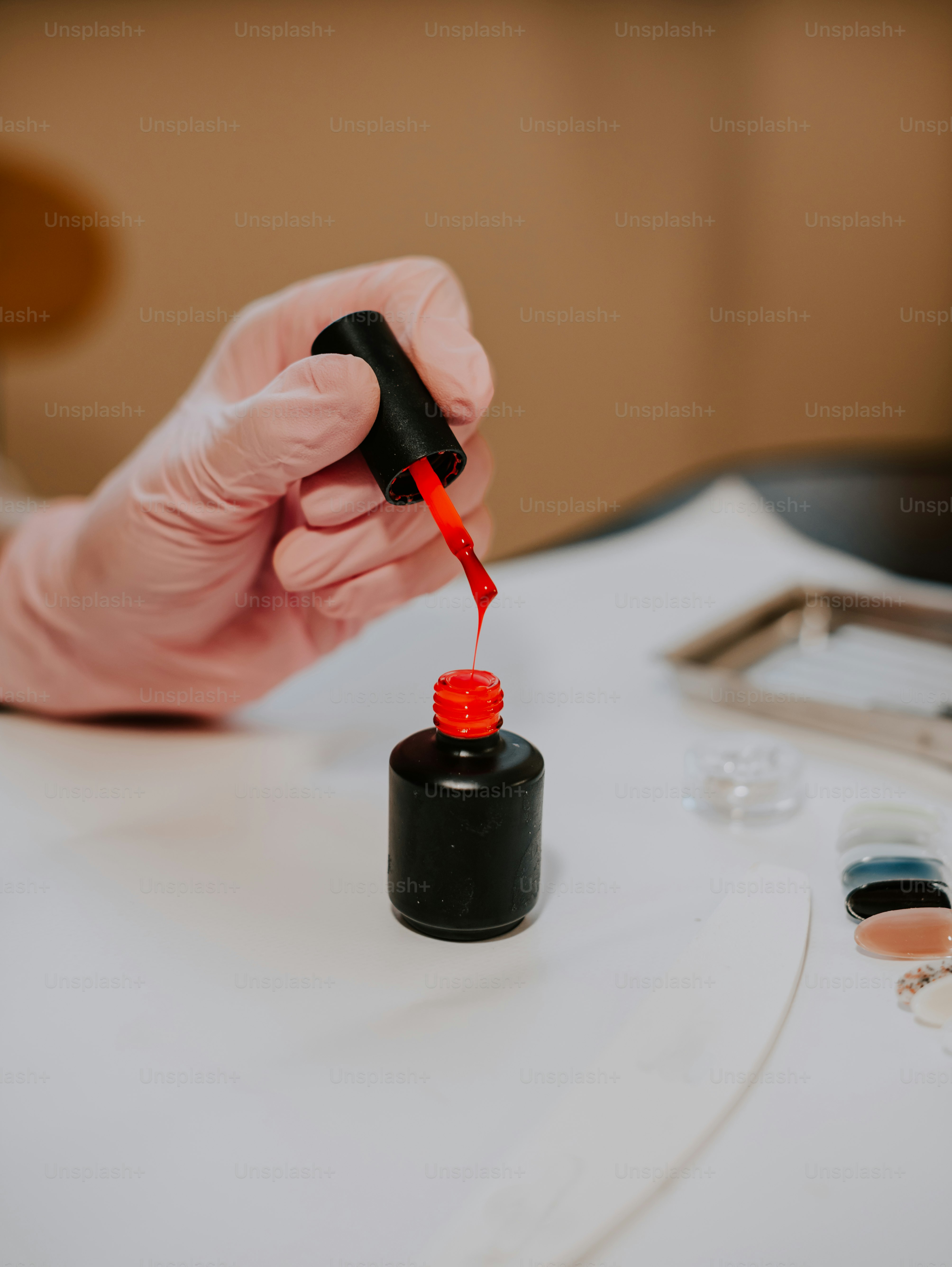 a gloved hand holding a bottle of red liquid