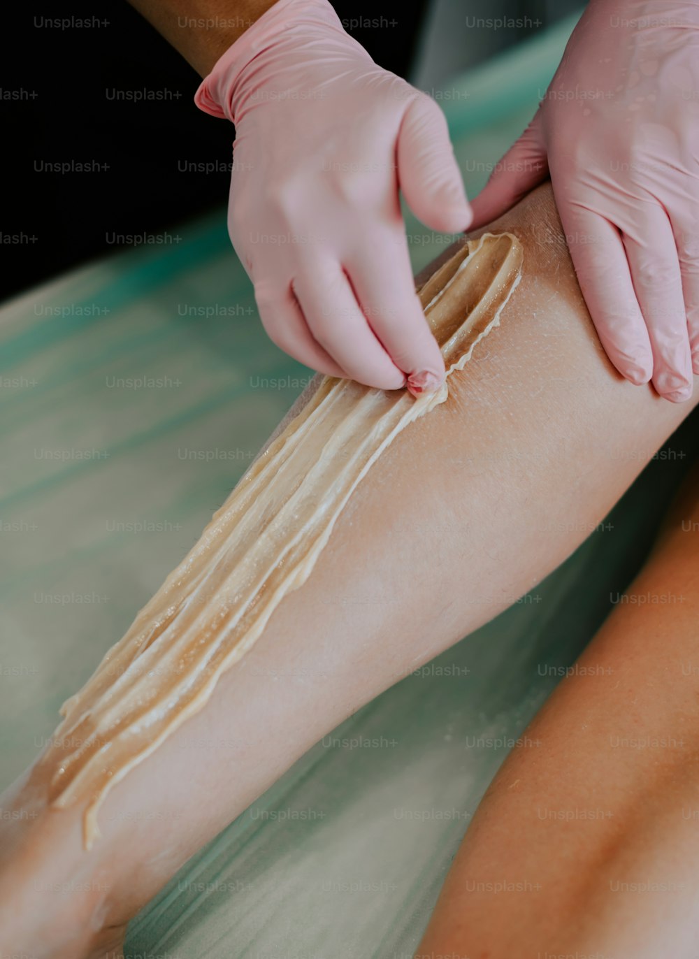 a person with a glove on is waxing a leg