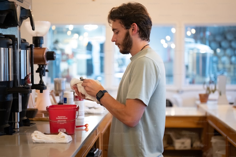 a man standing in a kitchen next to a red cup