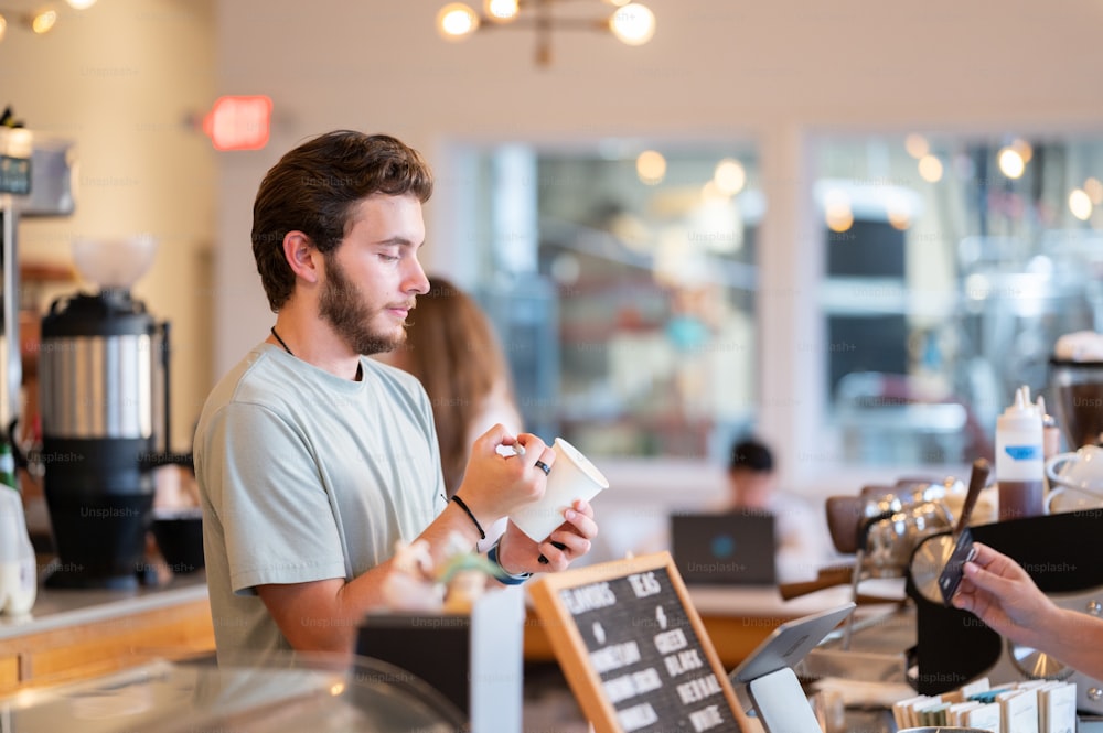 a man standing in front of a counter holding a cup